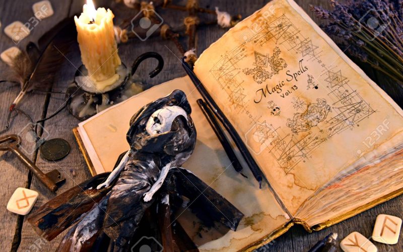 93654374-old-book-with-black-magic-spells-scary-doll-rune-and-burning-candle-on-planks-occult-esoteric-divina
